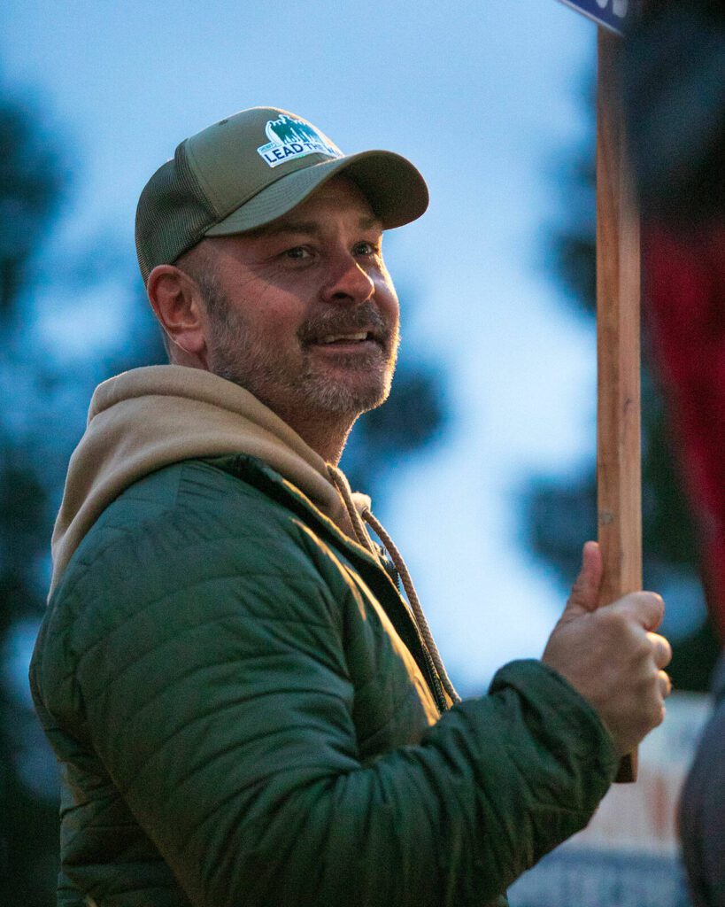 Snohomish County Sheriff Adam Fortney waves signs with supporters along Highway 9 on Monday, Nov. 6, 2023, in Arlington, Washington. (Ryan Berry / The Herald)
