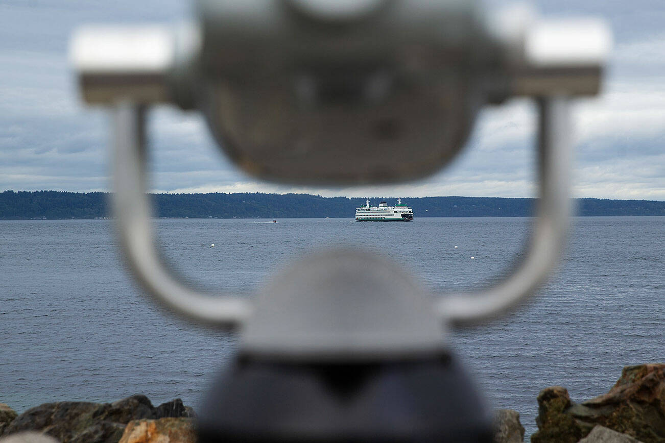 A Washington State Ferry is seen approaching Edmonds from beyond a telescope at Brackett’s Landing on Tuesday, Sept. 12, 2023, in Edmonds, Washington. (Ryan Berry / The Herald)