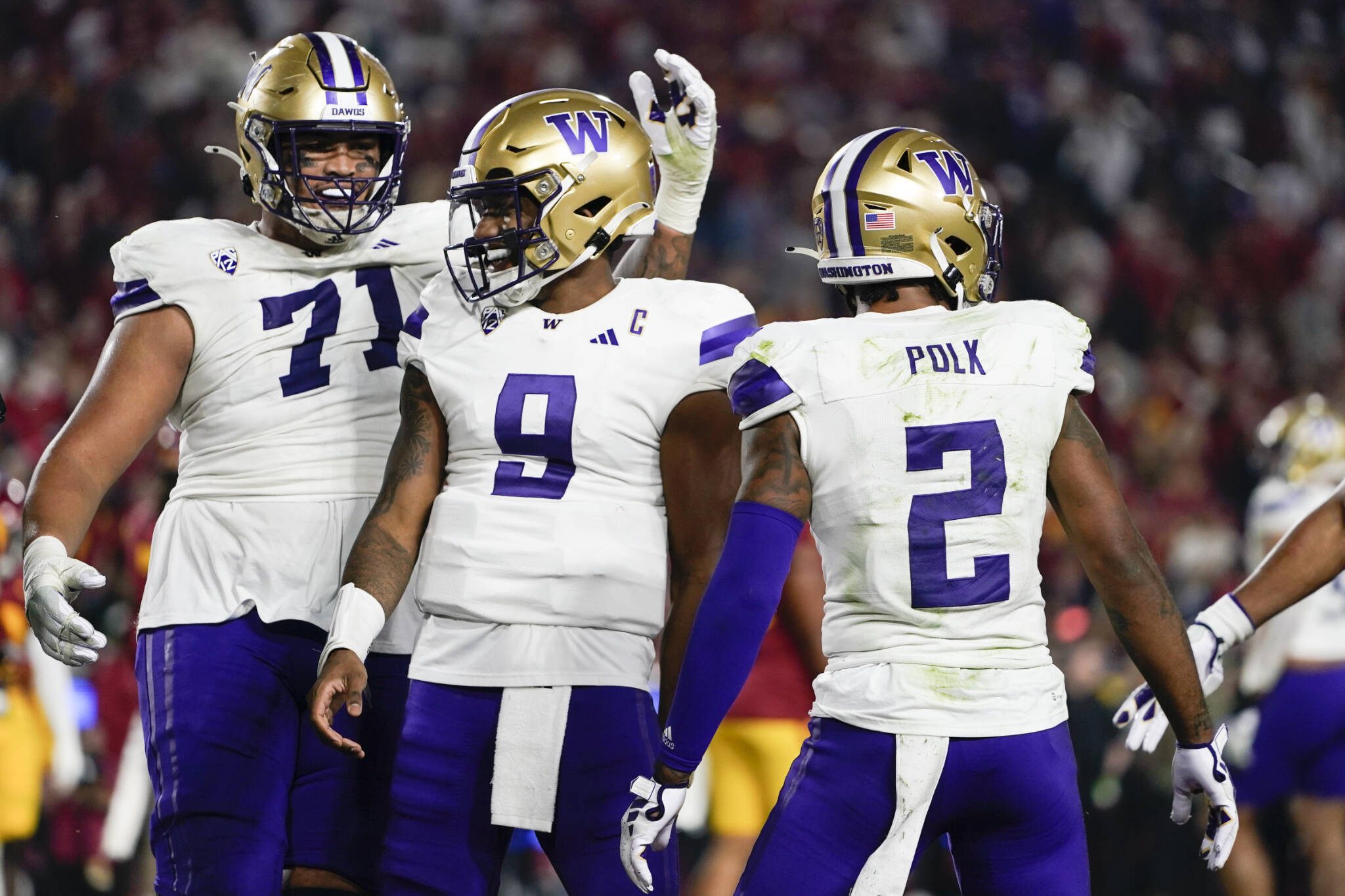 Washington offensive lineman Nate Kalepo (71) and quarterback Michael Penix Jr. (9) celebrate after a touchdown by wide receiver Ja’Lynn Polk (2) during a game against Southern California on Nov. 4 in Los Angeles. (AP Photo/Ryan Sun)