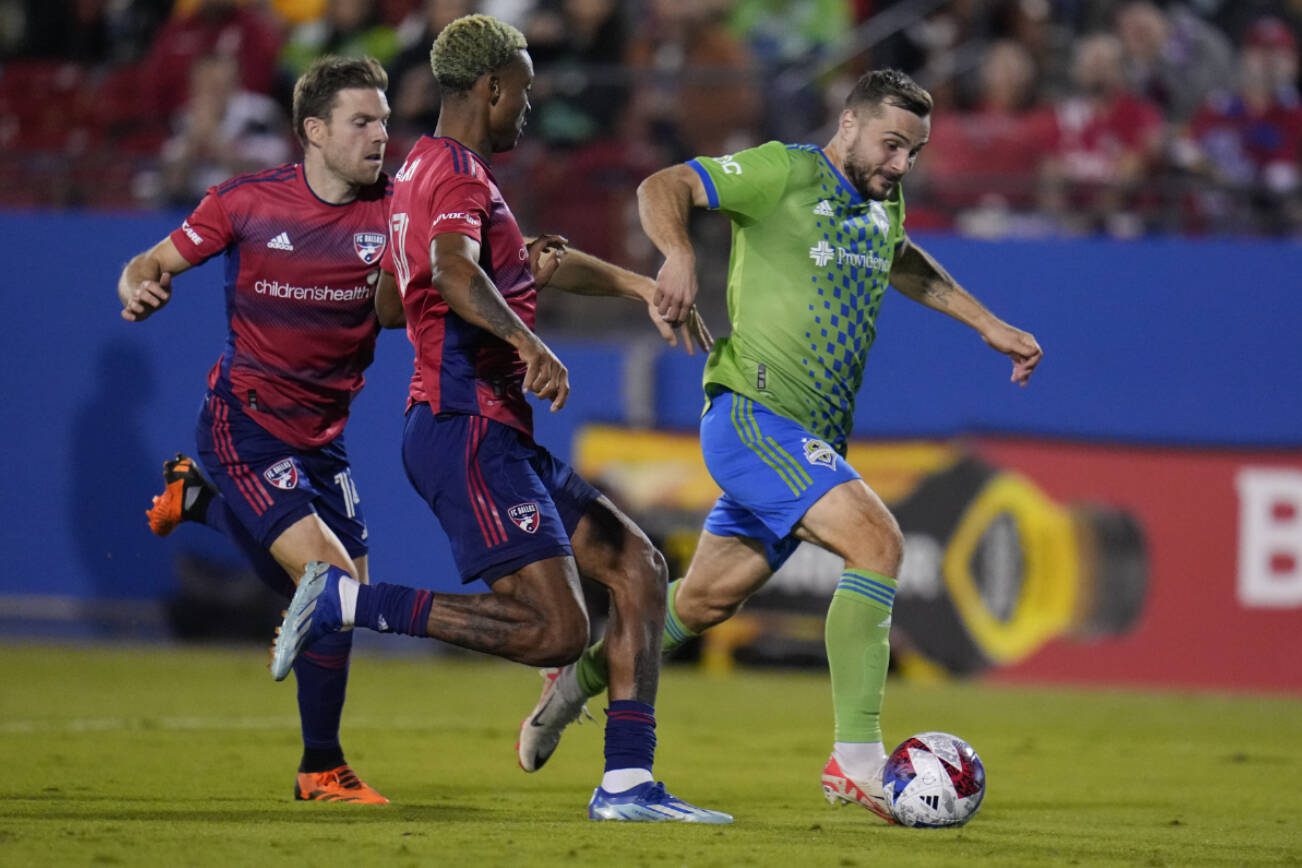 Seattle Sounders forward Jordan Morris, right, runs with the ball before scoring a goal in front of FC Dallas midfielder Asier Illarramendi, left, and defender Nkosi Tafari during the second half in Game 2 of a first round MLS playoff soccer match, Saturday, Nov. 4, 2023, in Frisco, Texas. (AP Photo/Julio Cortez)