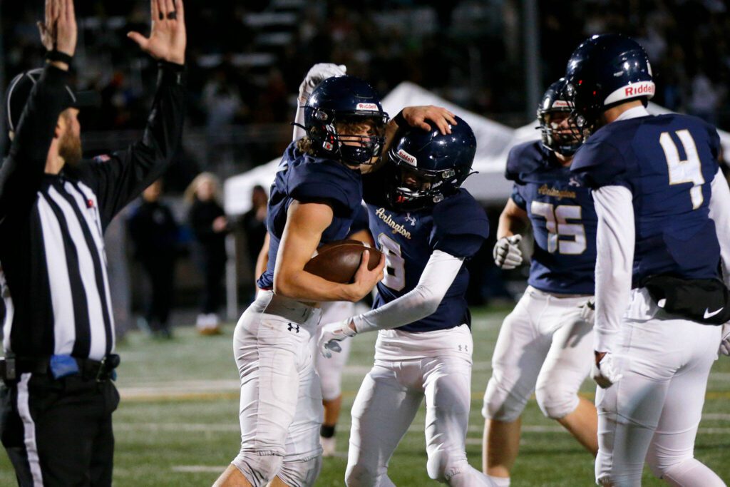 Arlington players celebrate Chase Deberry’s first quarter touchdown against Ridgeline during a playoff matchup Friday, Nov. 10, 2023, at Arlington High School in Arlington, Washington. (Ryan Berry / The Herald)

