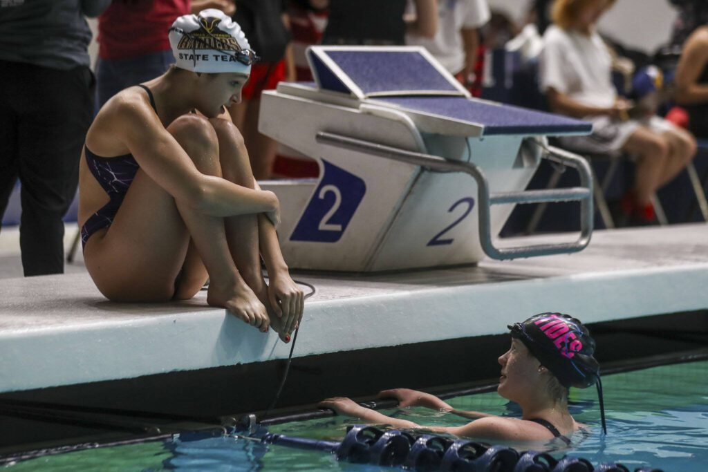 Swimmers chat before a race during the 3A girls state swim and dive championships at King County Aquatic Center in Federal Way, Washington on Saturday, Nov. 11, 2023. (Annie Barker / The Herald)
