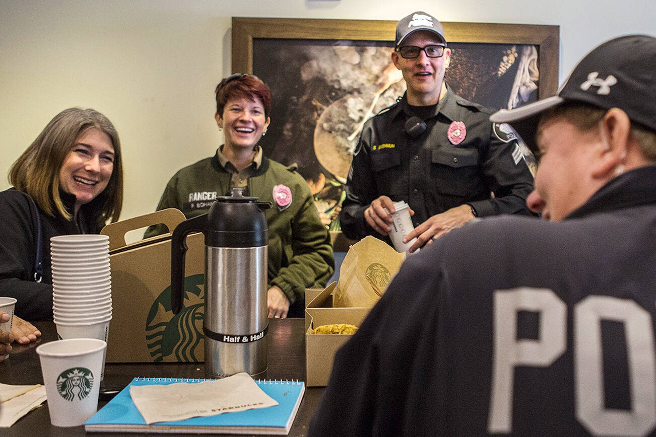 Nicole Kennedy, left, Ranger Peg Bonhan and Sergeant Shaun Greenmun chat with the pink badges on during the Mukilteo Police Department's Coffee with a Cop on Oct. 3, 2018 in Mukilteo, Wa. (Olivia Vanni / The Herald)