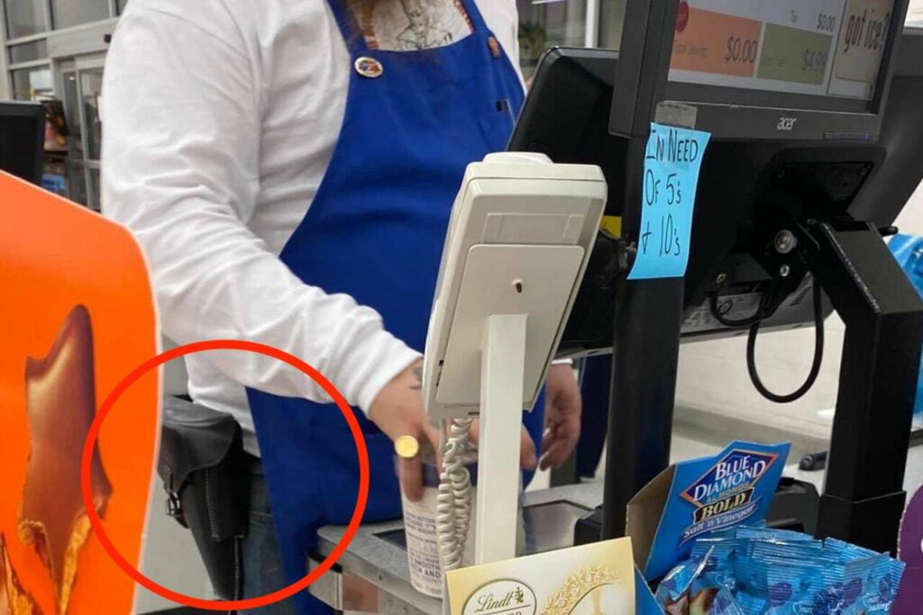 A Gold Bar Family Grocer employee checks out customers while wearing a Ku Klux Klan shirt that reads “I’m dreaming of a white Christmas,” KKK pins, and a loaded holster in Gold Bar, Washington. The photo was posted to the Gold Bar Facebook group on Saturday, Nov. 11, 2023. (Provided photo)
