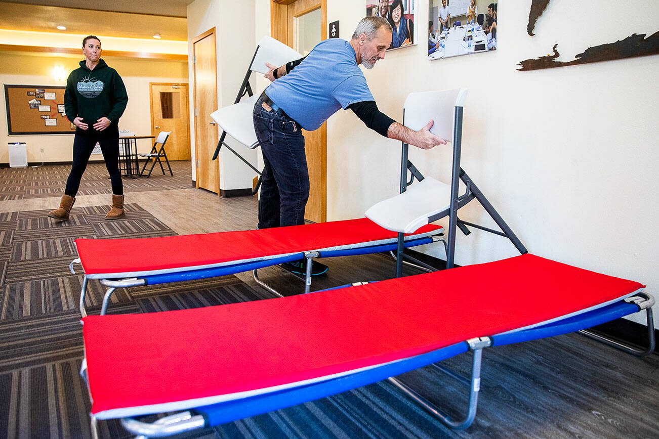 Roger Evans, New Hope Fellowship Church shelter coordinator, sets up two cots as examples of what is available to those that seek shelter at the church on Tuesday, Nov. 15, 2022, in Monroe, Washington. (Olivia Vanni / The Herald)