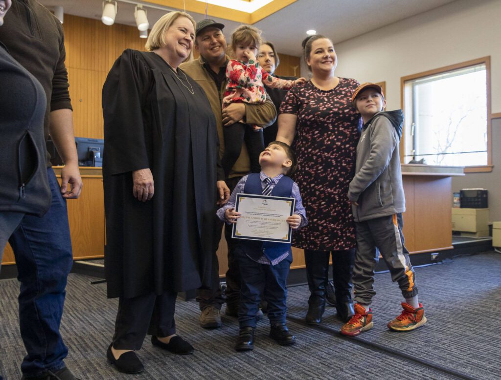 Joseph Andrew Bramlett, 3, center, looks up at Judge Judge after his adoption during National Adoption Day at the Snohomish County Courthouse on Friday, Nov. 17, 2023 in Everett, Washington. (Olivia Vanni / The Herald)
