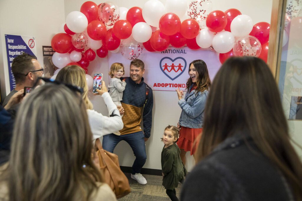 Families pause to take photos with a National Adoption Day sign on Friday, Nov. 17, 2023 in Everett, Washington. (Olivia Vanni / The Herald)
