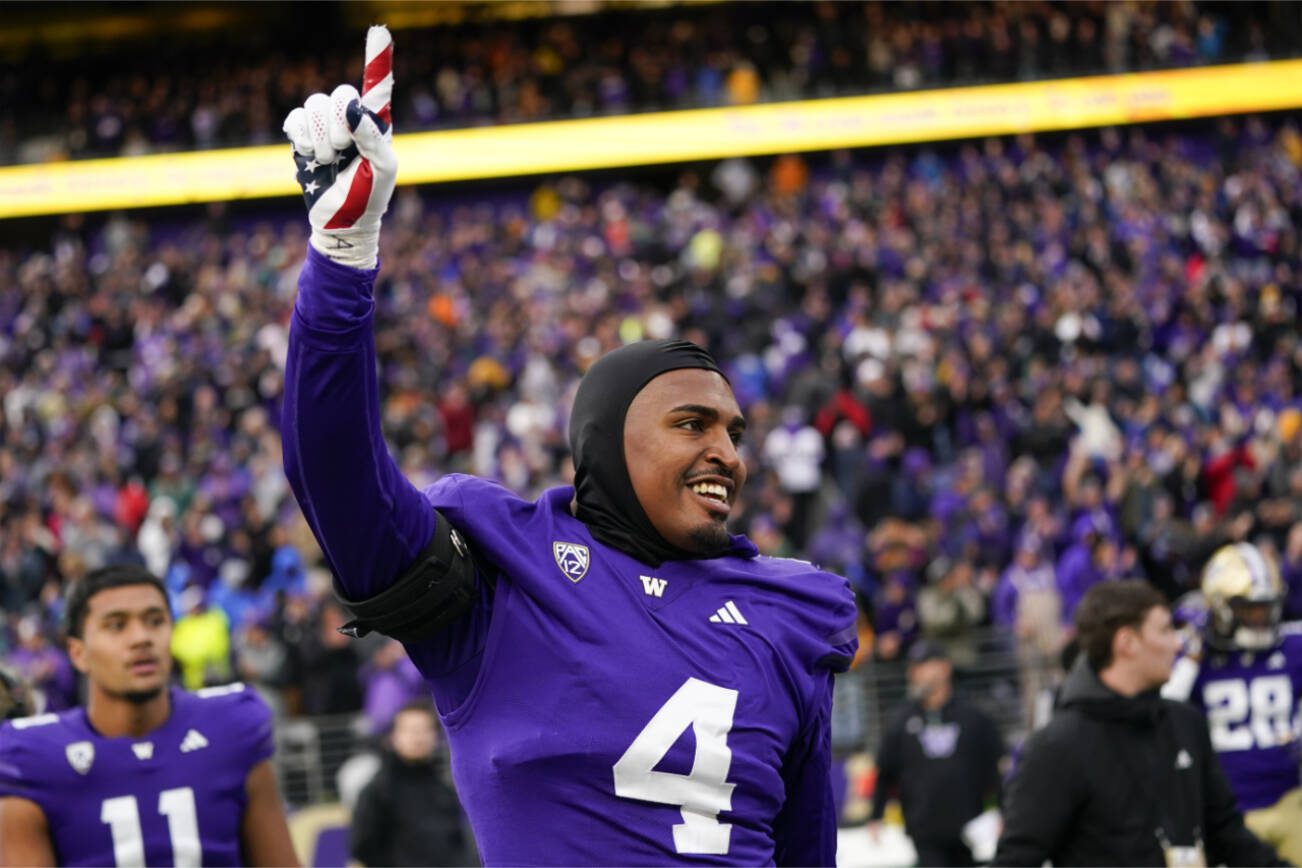 Washington defensive end Zion Tupuola-Fetui points as he walks onto the field to celebrate a 35-28 win over Utah in an NCAA college football game Saturday, Nov. 11, 2023, in Seattle. (AP Photo/Lindsey Wasson)