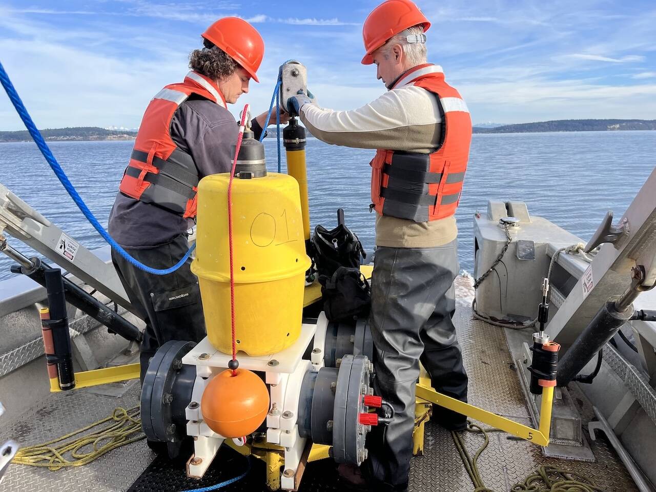 Sam Tabbutt and Jason Wood from SMRU Consulting connect an acoustic release to the hydrophone, so the boat can lower the device to the seabed and then disconnect from it. (Rachel Aronson)