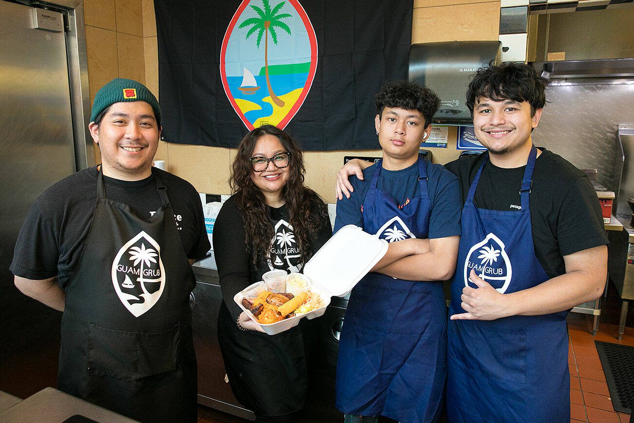 Guam Grub owner and head chef Julita Atoigue-Javier, center left, stands behind the counter with her brother-in-law Angelo Javier, left, and sons Timothy, 13, and John, 21, right, on Thursday, August 10, 2023, at the Everett Mall in Everett, Washington. (Ryan Berry / The Herald)