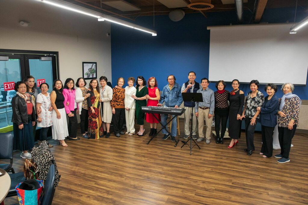 A group of seniors gather together for a group photo at the karaoke stage during a Vietnamese community lunch at the Homage Multicultural Senior Center on Wednesday, Nov. 15, 2023, in Lynnwood, Washington. (Ryan Berry / The Herald)
