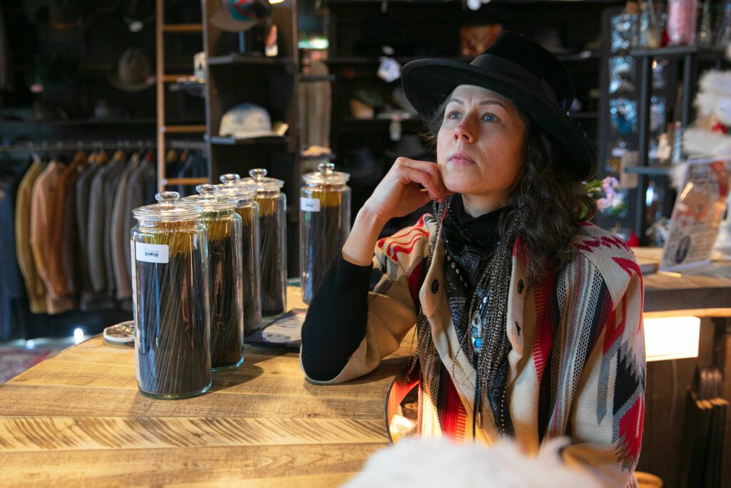 Jac Cash, owner of FauxyFurr Vintage + Handmade, sits behind the counter while speaking with a reporter on Saturday, Dec. 16, 2023, at her downtown Arlington, Washington storefront. (Ryan Berry / The Herald)
