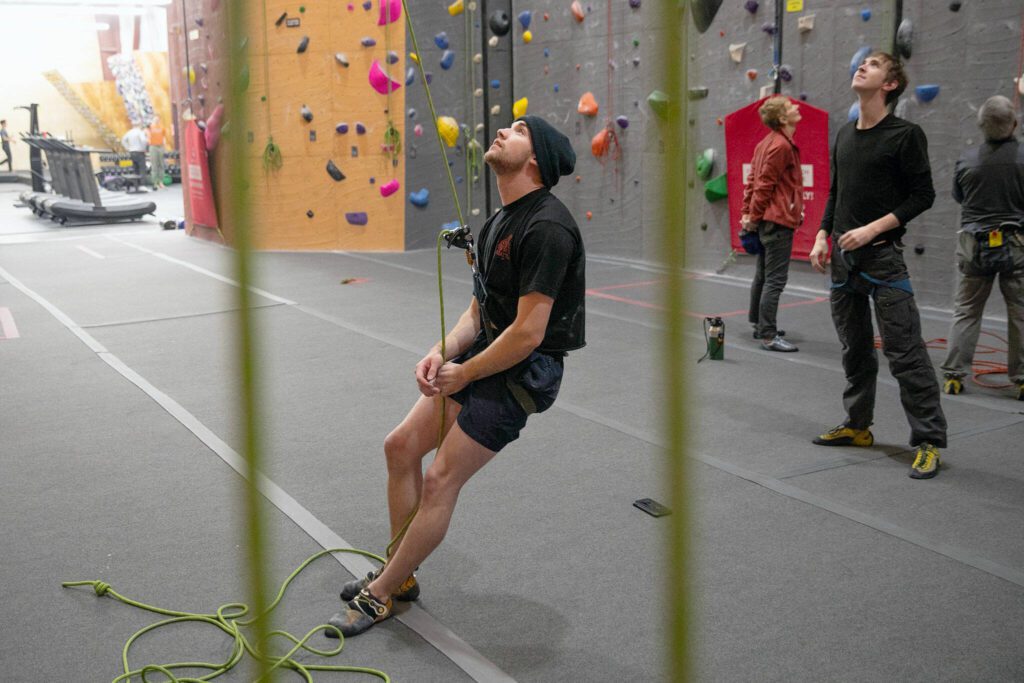 Andrew Koch, belaying, and Josiah Lee, right, look up and chat with top rope climber Elli Davey, not pictured, as the three climb together at Vertical World North on Monday, Nov. 20, 2023, in Lynnwood, Washington. (Ryan Berry / The Herald)
