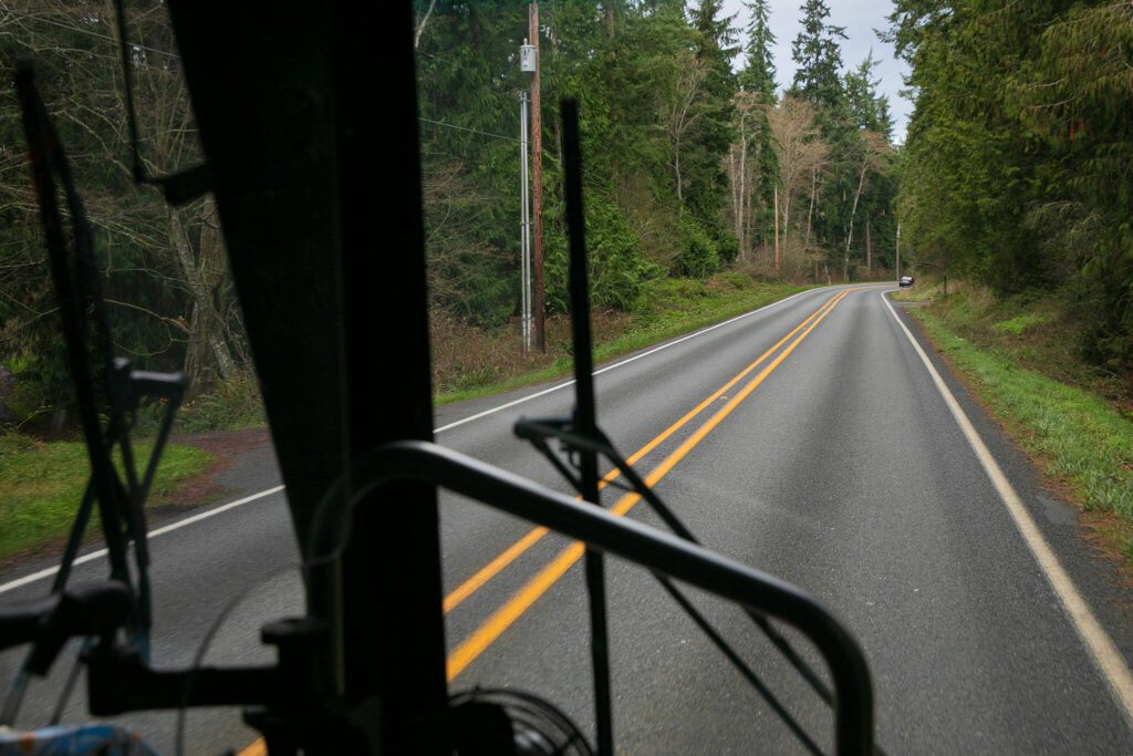 Island Transit buses weave through the woods and drive along the coast as they move up and down Whidbey Island on Tuesday, Dec. 19, 2023, near Oak Harbor, Washington. Driver Tino Gutierrez, a Texan who has been with Island Transit for 20 years, said he appreciates the beauty of his route and the friendliness of his riders. (Ryan Berry / The Herald)

