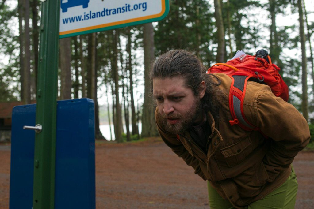 Herald reporter Jordan Hansen reads about a new Sunday route that takes riders to Deception Pass on Tuesday, Dec. 19, 2023, at Deception Pass State Park in Oak Harbor, Washington. (Ryan Berry / The Herald)
