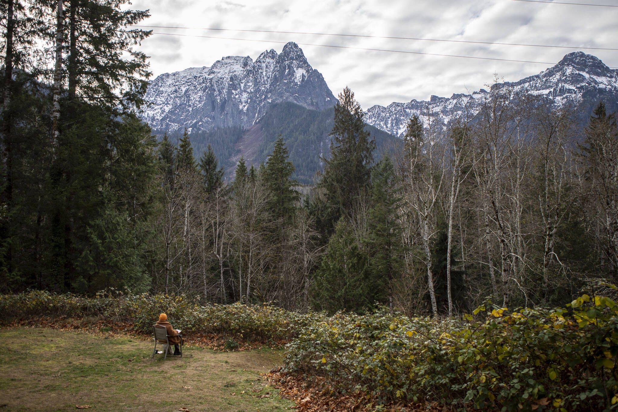 A person sits and looks out at Mt. Index in Index, Washington on Wednesday, Nov. 29, 2023.  (Annie Barker / The Herald)