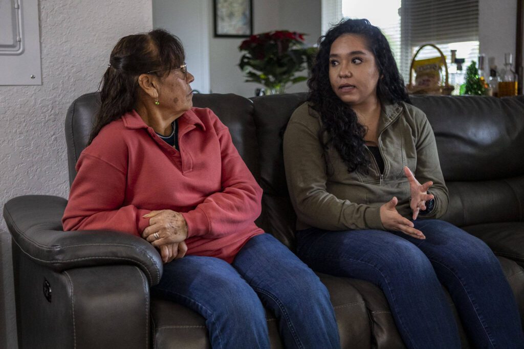 Elizabeth Cervantes, right, translates for her mother Maria Jimenez, left, at their home in Burlington, Washington on Wednesday, Dec. 6, 2023. (Annie Barker / The Herald)
