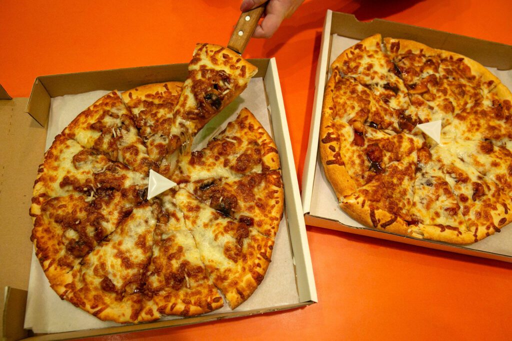 Ghengis Khan, left and General Tso’s Chicken pizzas at Pedeltweezer’s Chinese and Pizza on Wednesday, Dec. 6, 2023, in Arlington, Washington. (Ryan Berry / The Herald)
