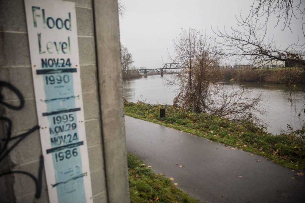 A sign showing the river levels of previous floods is visible along the Snohomish River on Monday, Dec. 4, 2023 in Snohomish, Washington. (Olivia Vanni / The Herald)
