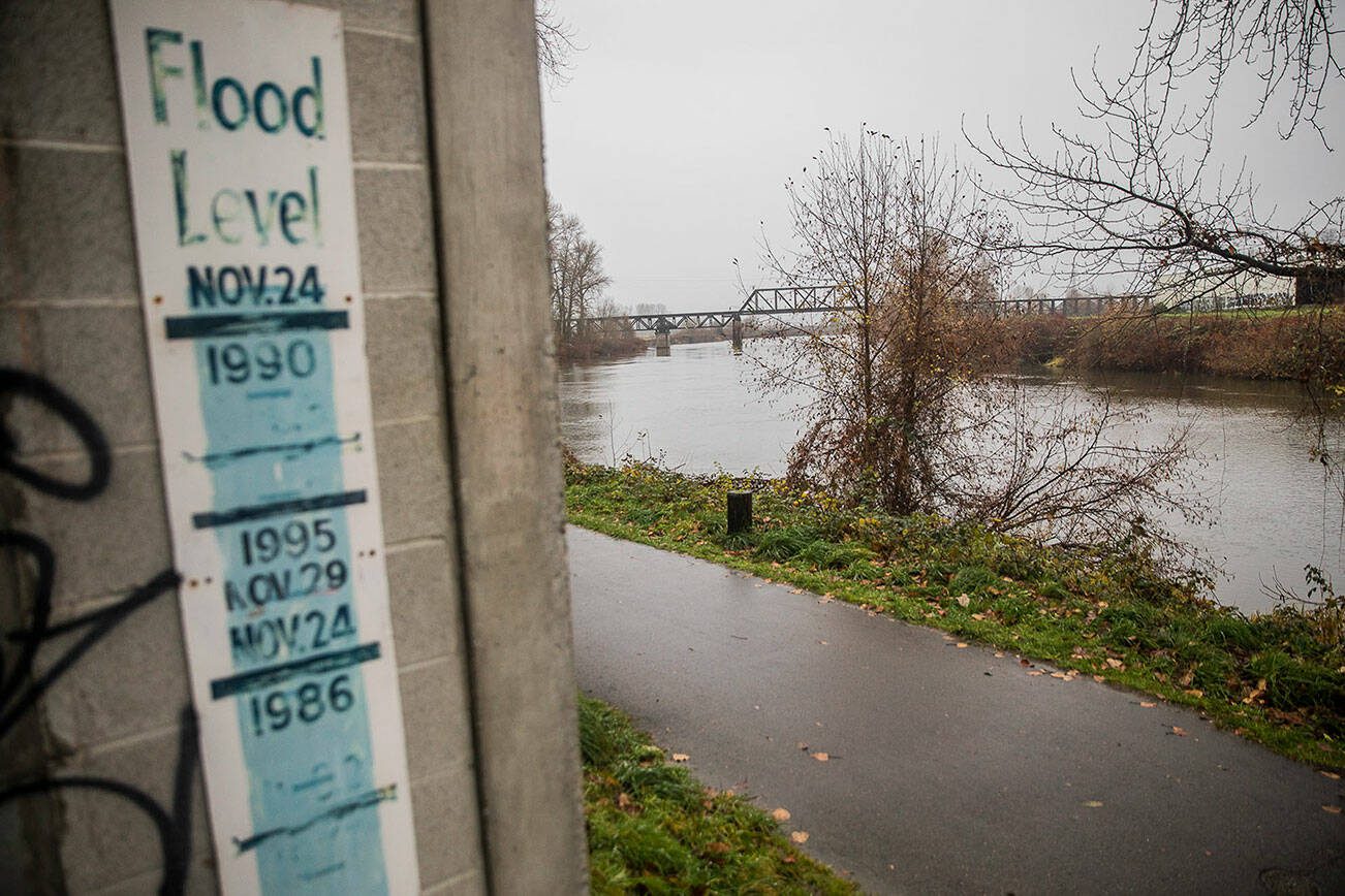 A sign showing the river levels of previous floods is visible along the Snohomish River on Monday, Dec. 4, 2023 in Snohomish, Washington. (Olivia Vanni / The Herald)