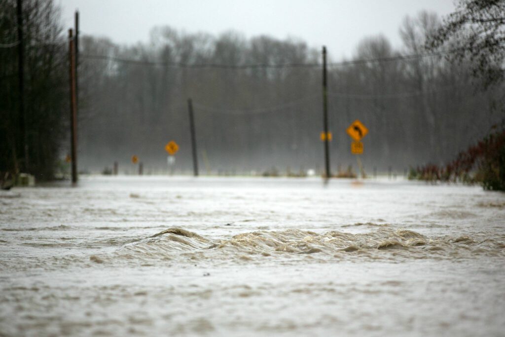 Water from the Stillaguamish rapidly flows over Pioneer Highway during heavy flooding on Tuesday, Dec. 5, 2023, just north of Silvana, Washington. (Ryan Berry / The Herald)

