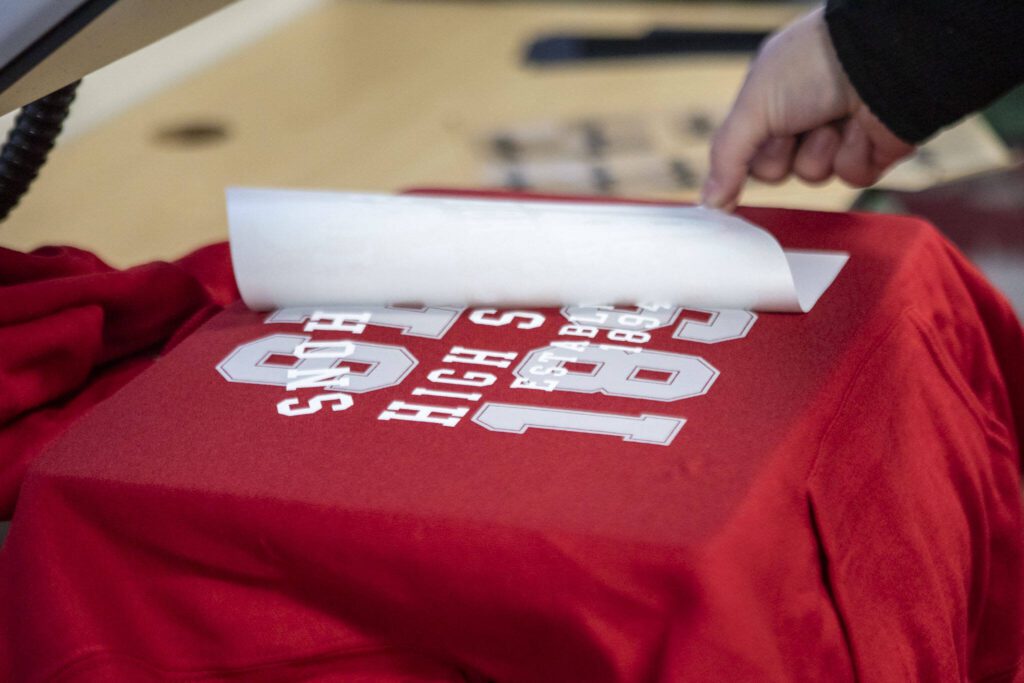 Senior Hailey Jardine uses the new heat press for DECA to make school apparel at Snohomish High School in Snohomish, Washington on Wednesday, Dec. 13, 2023. DECA is a national nonprofit for students interested in business. (Annie Barker / The Herald)
