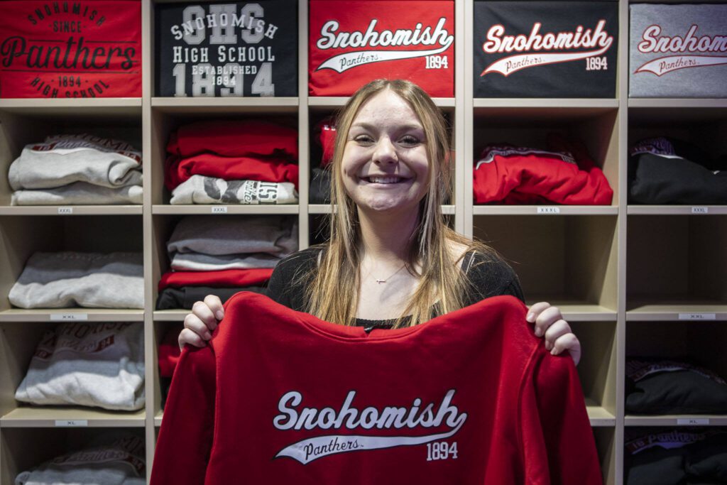 Senior Hailey Jardine poses for a photo with a sweatshirt she made using the new heat press for DECA at Snohomish High School in Snohomish, Washington on Wednesday, Dec. 13, 2023. DECA is a national nonprofit for students interested in business. (Annie Barker / The Herald)
