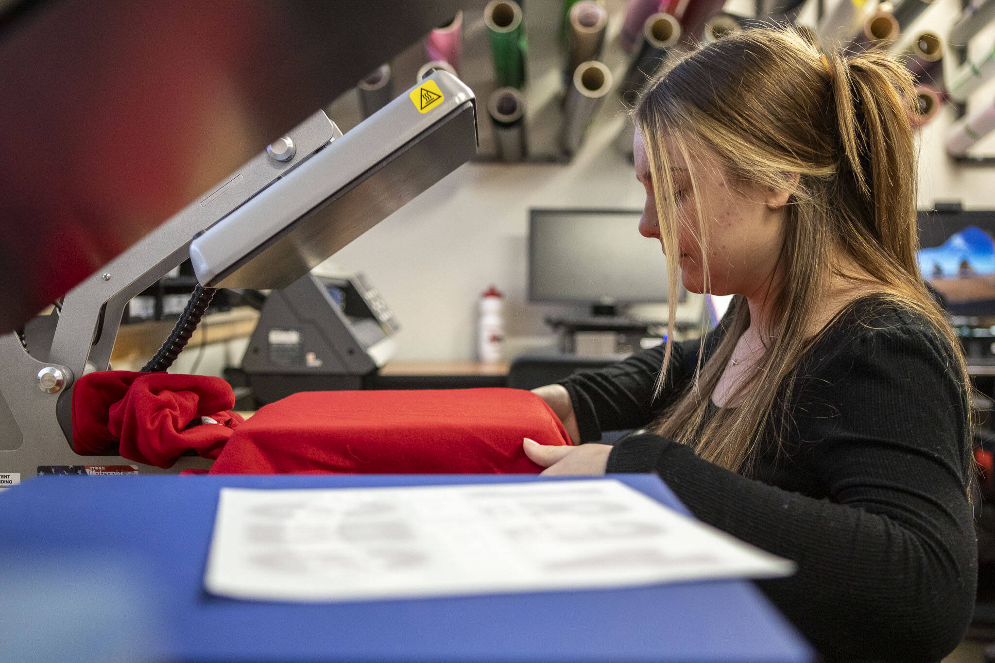Senior Hailey Jardine uses the new heat press for DECA to make school apparel at Snohomish High School in Snohomish, Washington on Wednesday, Dec. 13, 2023.  DECA is a national nonprofit for students interested in business. (Annie Barker / The Herald)
