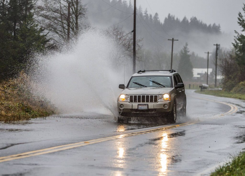 A car drives through standing water on Ben Howard Road on Tuesday, Dec. 5, 2023 in Monroe, Washington. (Olivia Vanni / The Herald)

