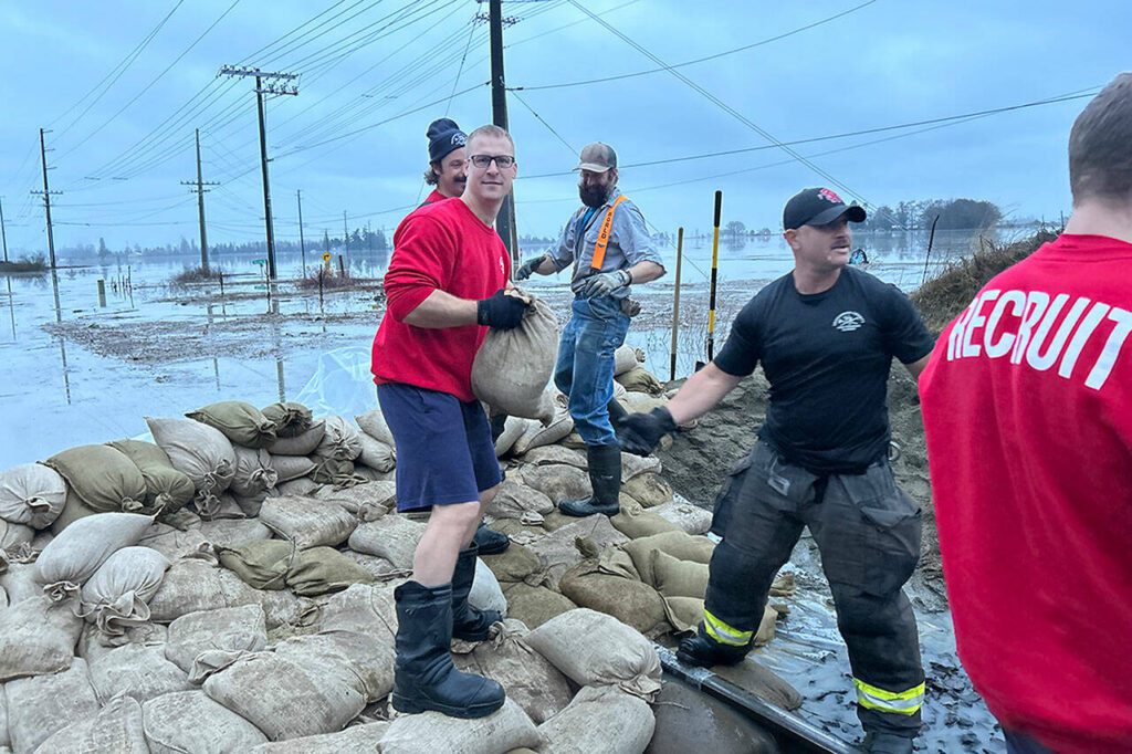 Firefighters and recruits from all over Snohomish County place sandbags Wednesday morning near the Stillaguamish River along Highway 532 to protect Stanwood, Washington from flooding. (South County Fire)
