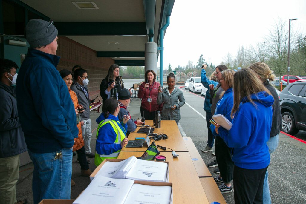 Endeavour Elementary teachers and staff quickly gather while working together to hand out laptops and class materials to hundreds of families on Wednesday, Dec. 6, 2023, two days after an overnight fire inside the school in Mukilteo, Washington. (Ryan Berry / The Herald)
