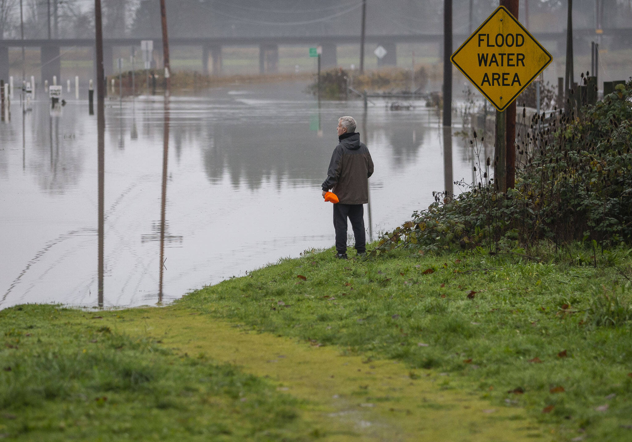 A man pauses to look out over the flooding along Old Snohomish Monroe Road on Wednesday, Dec. 6, 2023 in Snohomish, Washington. (Olivia Vanni / The Herald)