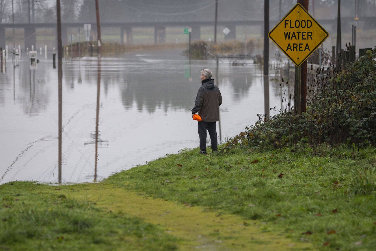 A man pauses to look out over the flooding along Old Snohomish Monroe Road on Wednesday, Dec. 6, 2023 in Snohomish, Washington. (Olivia Vanni / The Herald)