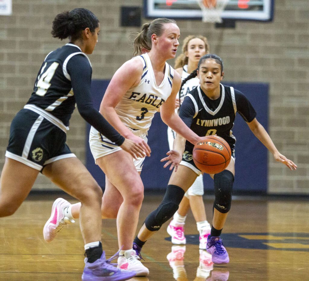 Arlington’s Rachel Snow dribbles the ball while being double teamed during the game against Lynnwood on Monday, Dec. 11, 2023 in Arlington, Washington. (Olivia Vanni / The Herald)
