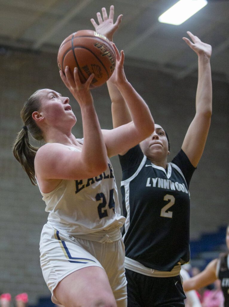 Arlington’s Katie Snow tries to make a layup while being guarded by Lynnwood’s Kayla Lorenz during the game on Monday, Dec. 11, 2023 in Arlington, Washington. (Olivia Vanni / The Herald)
