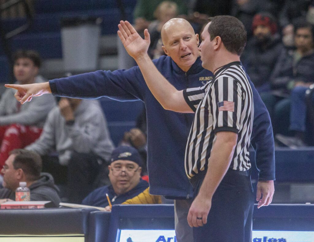 Arlington head coach Joe Marsh has a discussion with one of the referees about an in correct call during the game against Lynnwood on Monday, Dec. 11, 2023 in Arlington, Washington. (Olivia Vanni / The Herald)
