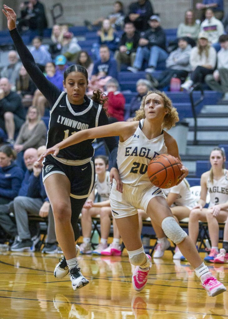 Arlington’s Samara Morrow drives to the hoop while being guarded by Lynnwood’s Teyah Clark during the game on Monday, Dec. 11, 2023 in Arlington, Washington. (Olivia Vanni / The Herald)
