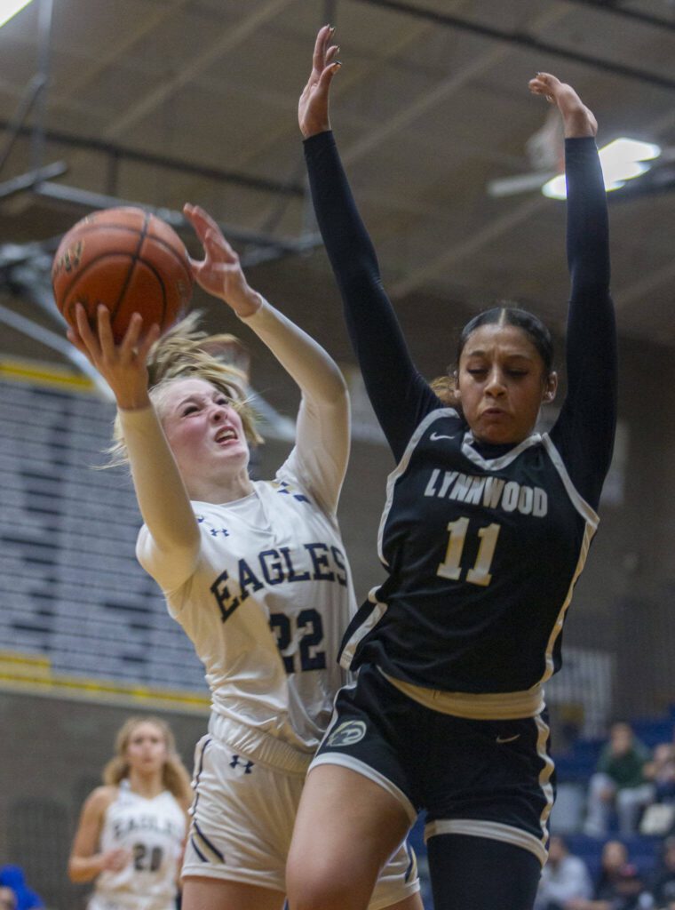 Lynnwood’s Teyah Clark leaps in the air to block a shot by Arlington’s Kierra Reese during the game on Monday, Dec. 11, 2023 in Arlington, Washington. (Olivia Vanni / The Herald)
