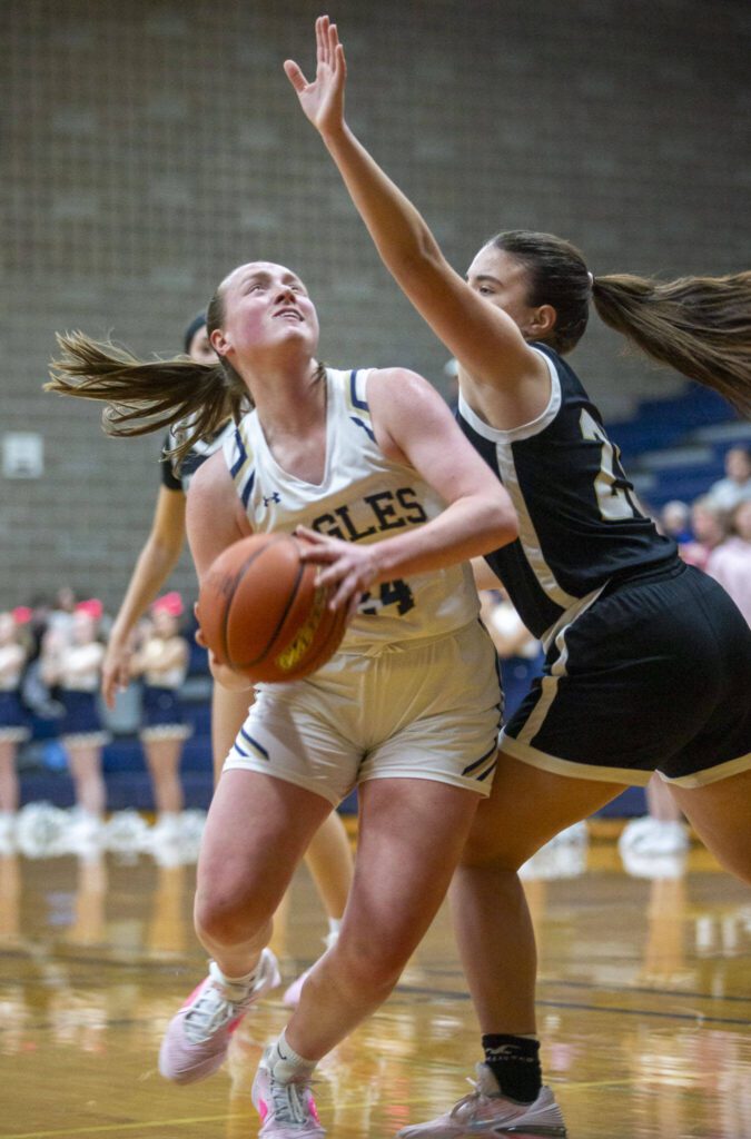 Arlington’s Katie Snow tries to make a layup while being guarded by Lynnwood’s Ena Dodik during the game on Monday, Dec. 11, 2023 in Arlington, Washington. (Olivia Vanni / The Herald)
