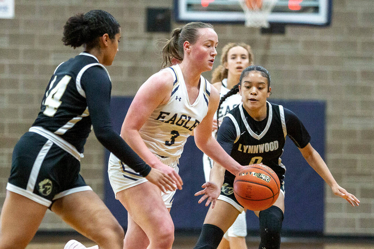 Arlington’s Rachel Snow dribbles the ball while being double teamed during the game against Lynnwood on Monday, Dec. 11, 2023 in Arlington, Washington. (Olivia Vanni / The Herald)