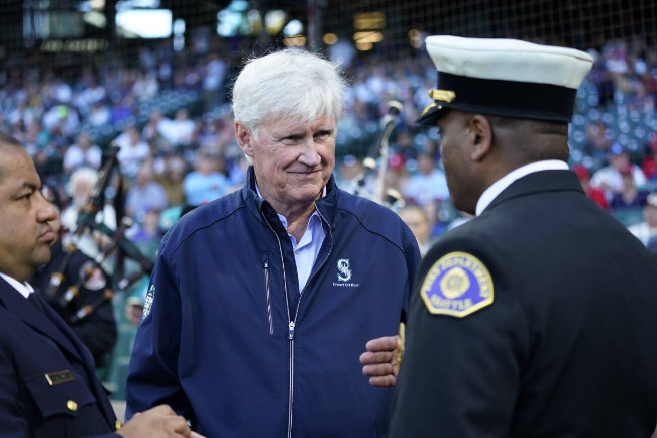 Seattle Mariners owner John Stanton, center, talks with Seattle Police chief Adrian Diaz, left, and Seattle Fire Department chief Harold Scoggins, right, before a baseball game between the Seattle Mariners and the Los Angeles Angels, Monday, Sept. 11, 2023, in Seattle. (AP Photo/Lindsey Wasson)