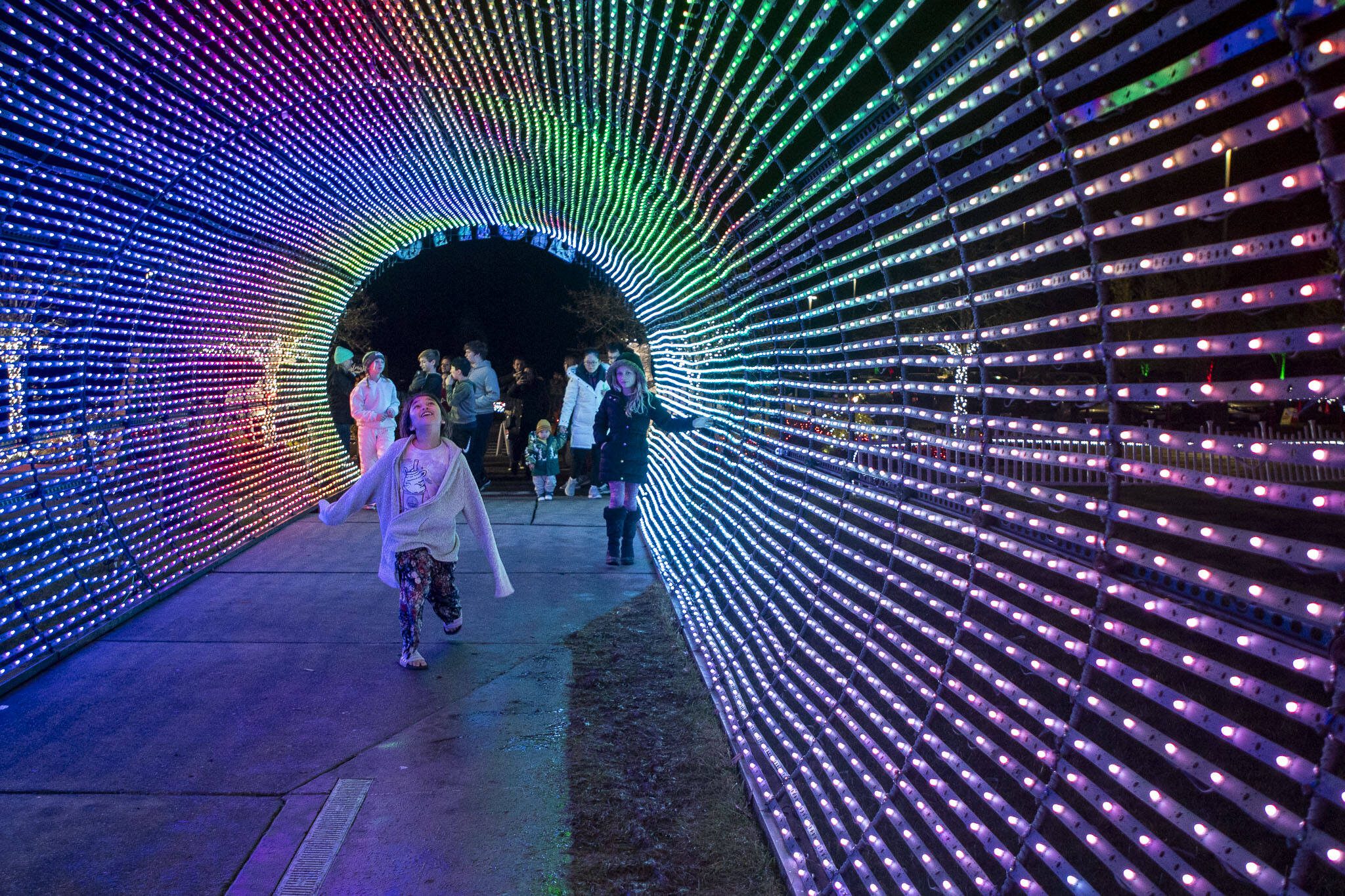 People walk through a tunnel of lights at Evergreen Church in Bothell, Washington, on Monday, Dec. 11, 2023. (Annie Barker / The Herald)