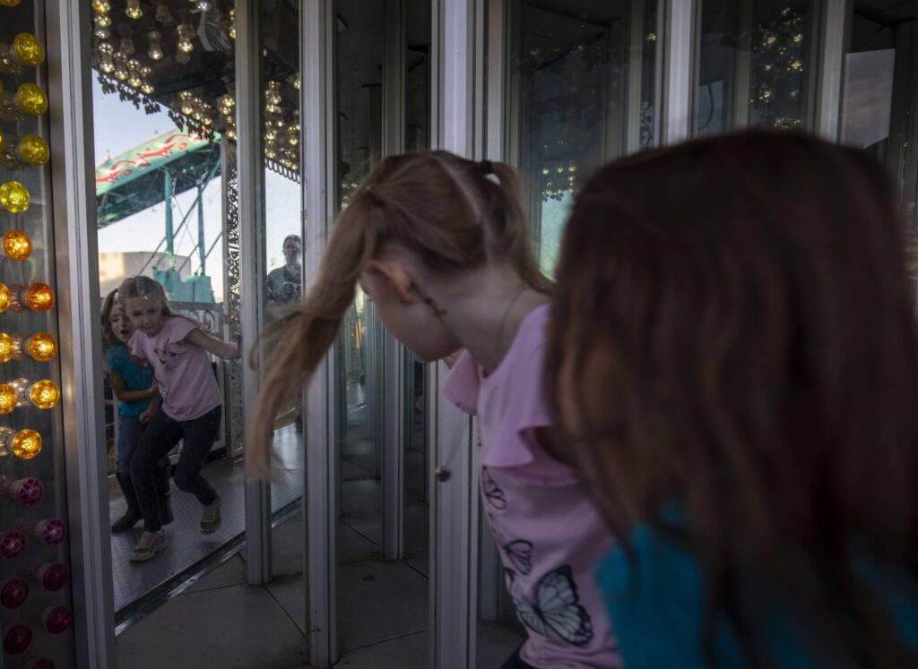 Children enter a house of mirrors during the Kla Ha Ya Days carnival at Harvey Field on Thursday, July 13, 2023, in Snohomish, Washington. (Annie Barker / The Herald)
