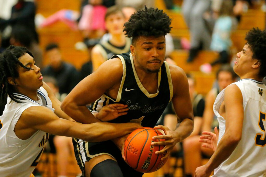 Lake Stevens’ Javon McFerrin tries to bull his way through two defenders against Mariner on Feb. 2 at Mariner High School in Everett. (Ryan Berry / The Herald)
