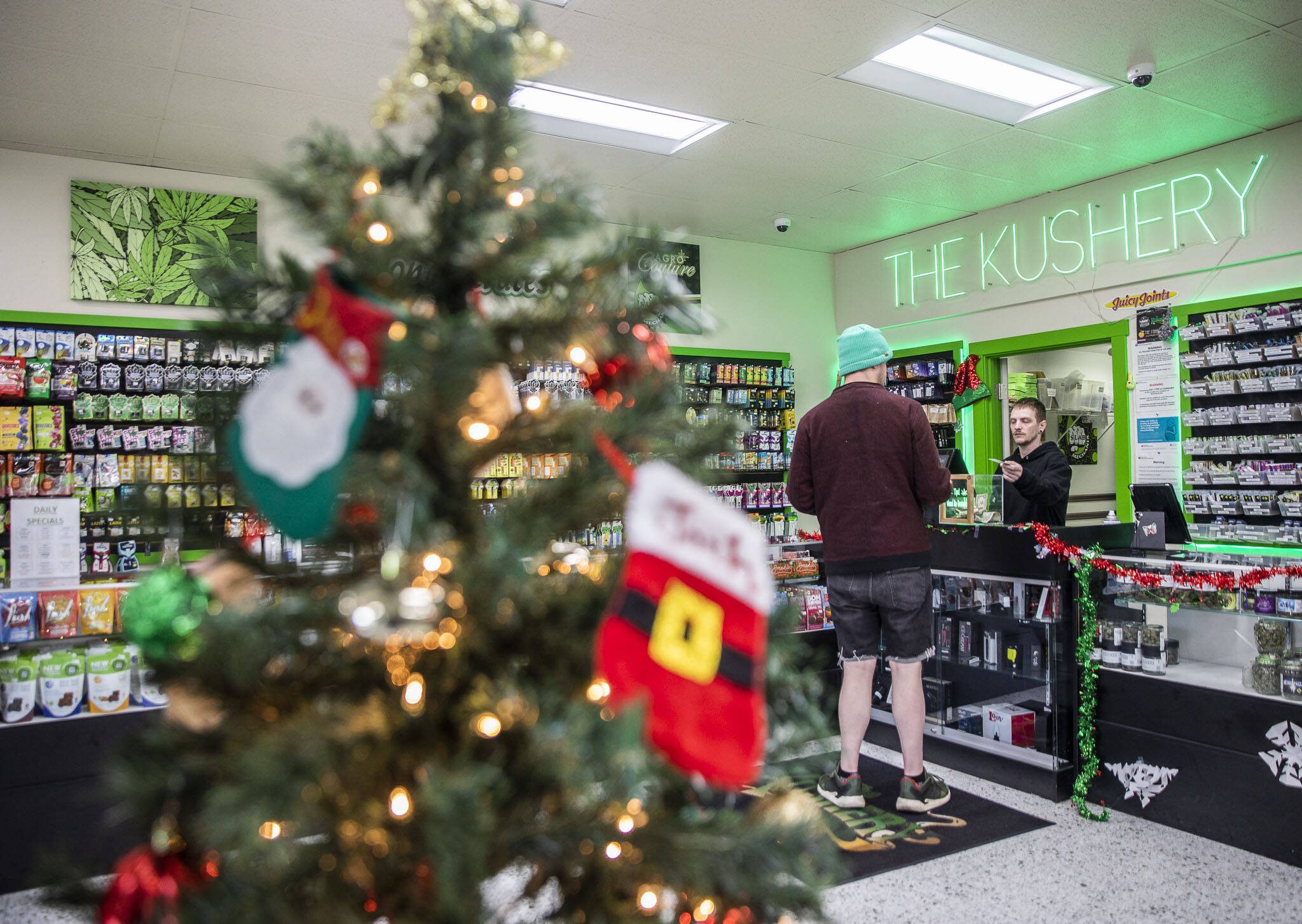 Matt Folmsbee, right, helps a customer at The Kushery on Friday, Dec. 15, 2023 in Everett, Washington. (Olivia Vanni / The Herald)