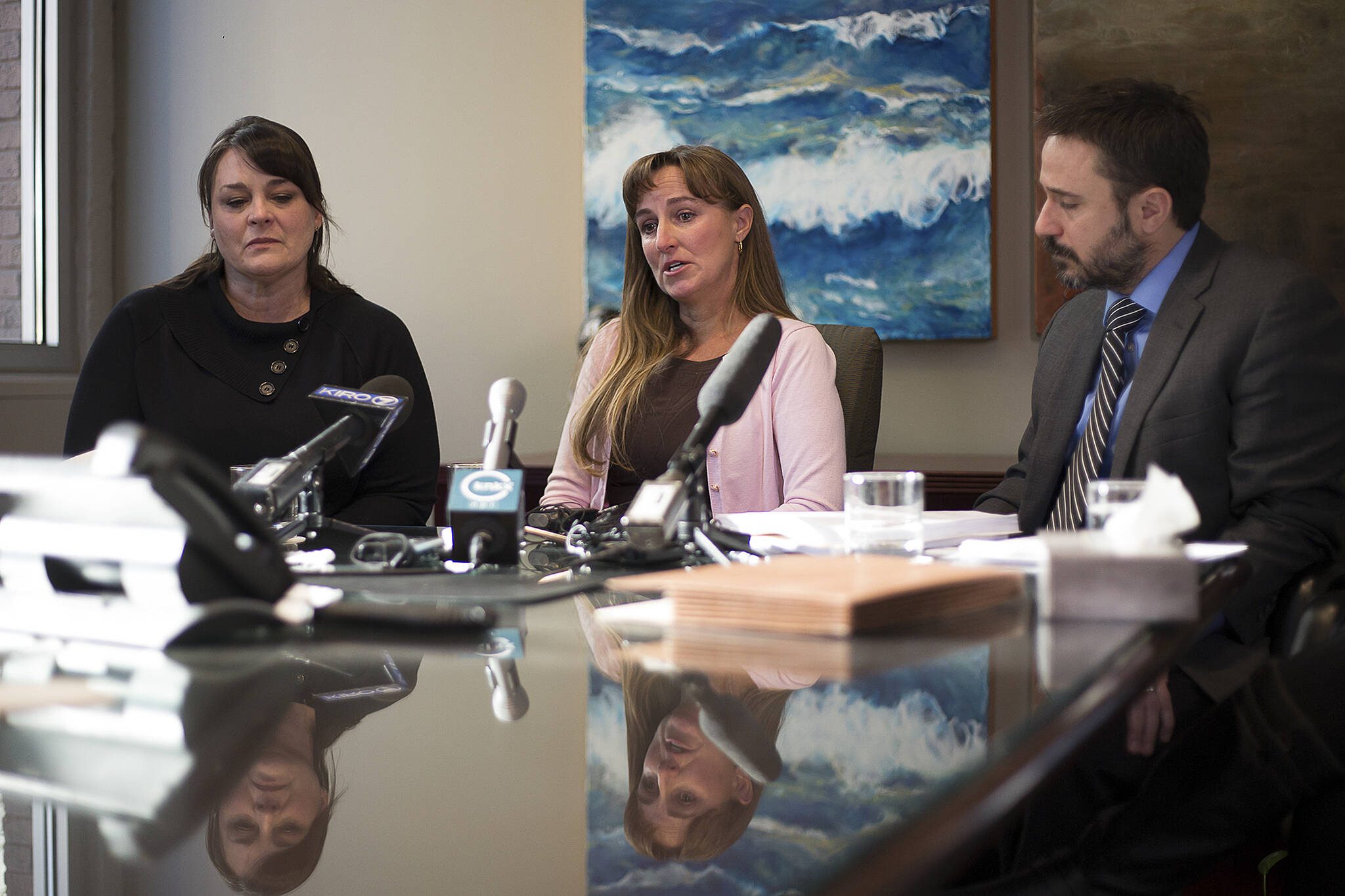 Stacy Mullen-Deland (center) gives an account of health issues faced by her children as Jill Savery (left) and attorney Sean Gamble listen during a press conference in downtown Seattle on Jan. 3, 2018. Mullen-Deland and 35 others sued Monsanto and the state on Tuesday, alleging a toxic environment at Sky Valley in Monroe has made them sick. (David Rzegocki)