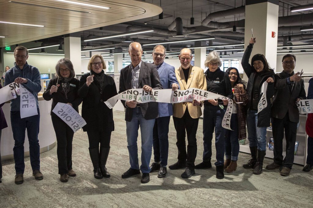 Community members cut a ribbon and celebrate during the grand reopening of the Edmonds Library in Edmonds, Washington on Saturday, Jan. 13, 2024. (Annie Barker / The Herald)

