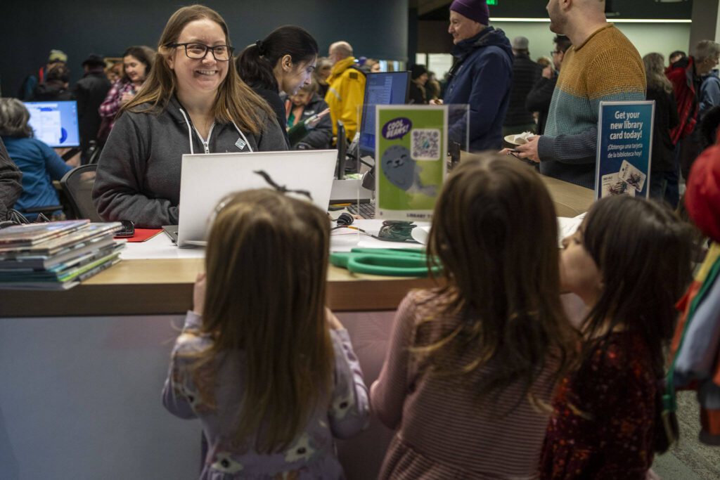 Librarian Vanesa Gutierrez checks out books to patrons during the grand reopening of the Edmonds Library in Edmonds, Washington on Saturday, Jan. 13, 2024. (Annie Barker / The Herald)
