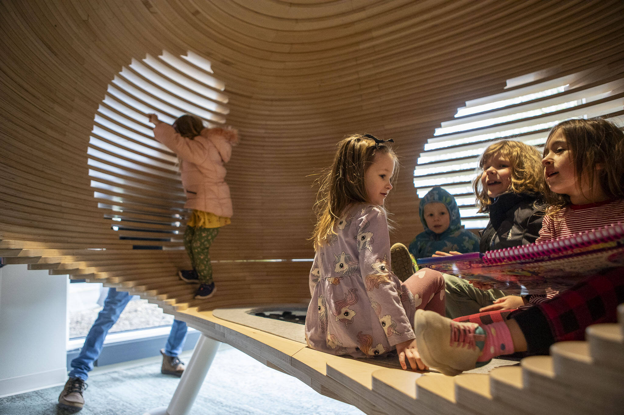 Lola Ernsting, 6, second from left, and Sofia Banan, 6, far right, play with other kids in a structure meant for reading during the grand reopening of the Edmonds Library in Edmonds, Washington on Saturday, Jan. 13, 2024. (Annie Barker / The Herald)