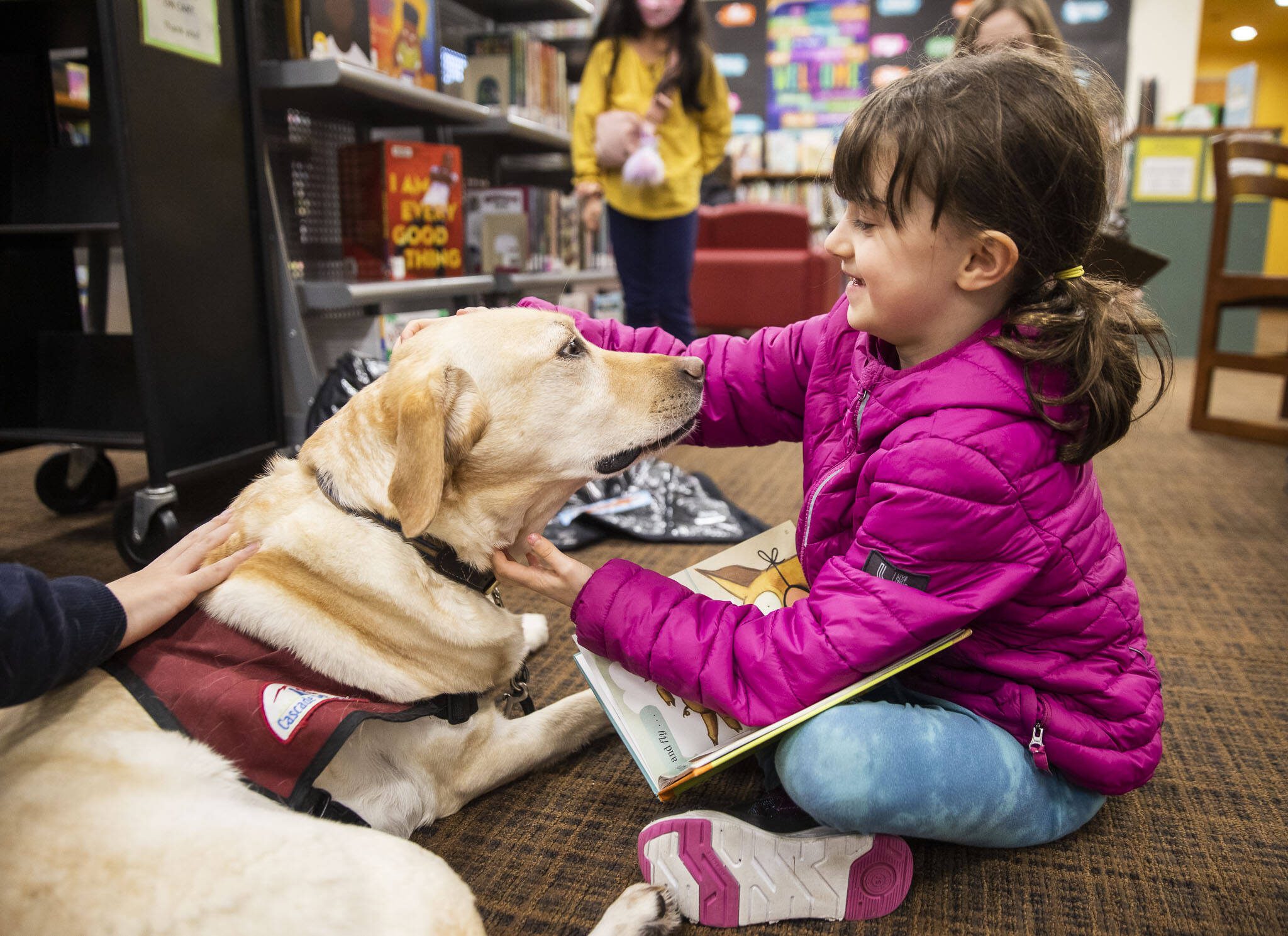 Noemie Leibov, 8, pauses reading aloud to pet Strummer during Tails and Tales at the Mukilteo Library on Wednesday, Jan. 17, 2024 in Mukilteo, Washington. (Olivia Vanni / The Herald)